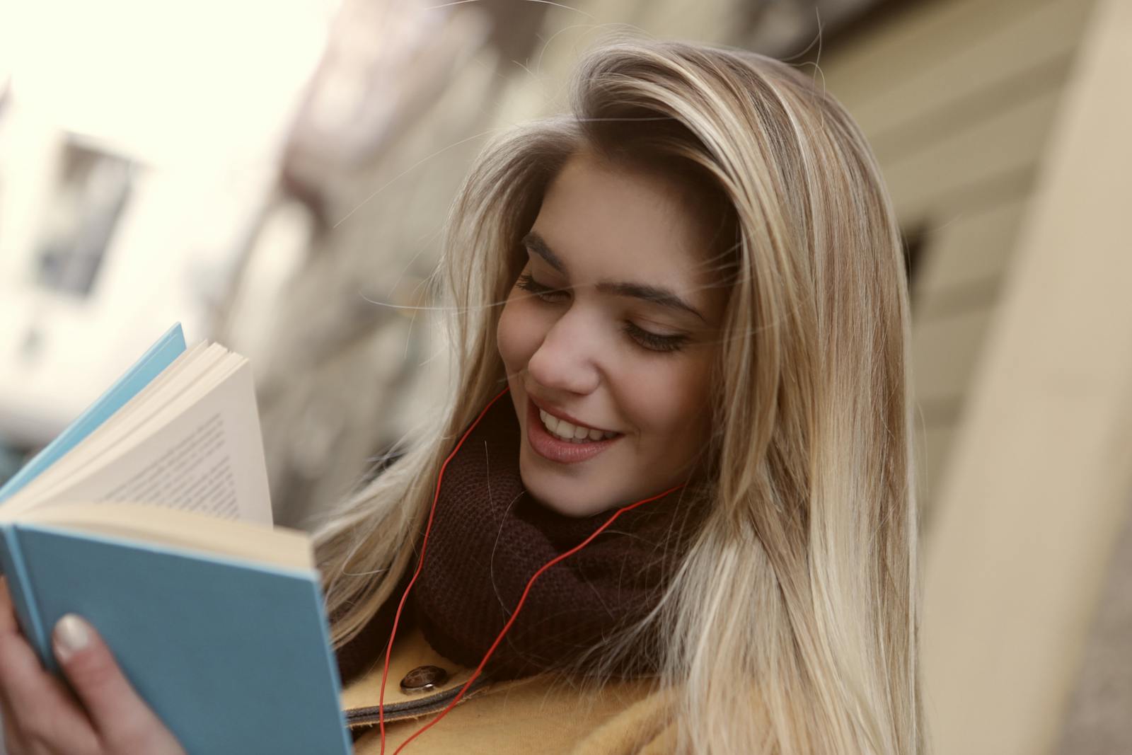 Smiling woman with headphones reading a book and enjoying a peaceful moment.